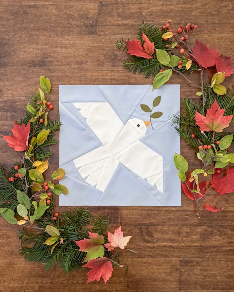 A white dove holding a green spring on a light blue background.