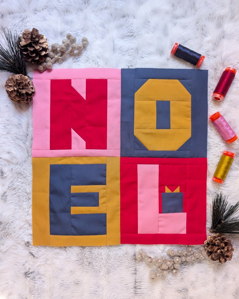 Patwork letters in red, pink, blue and gold that spell Noel.